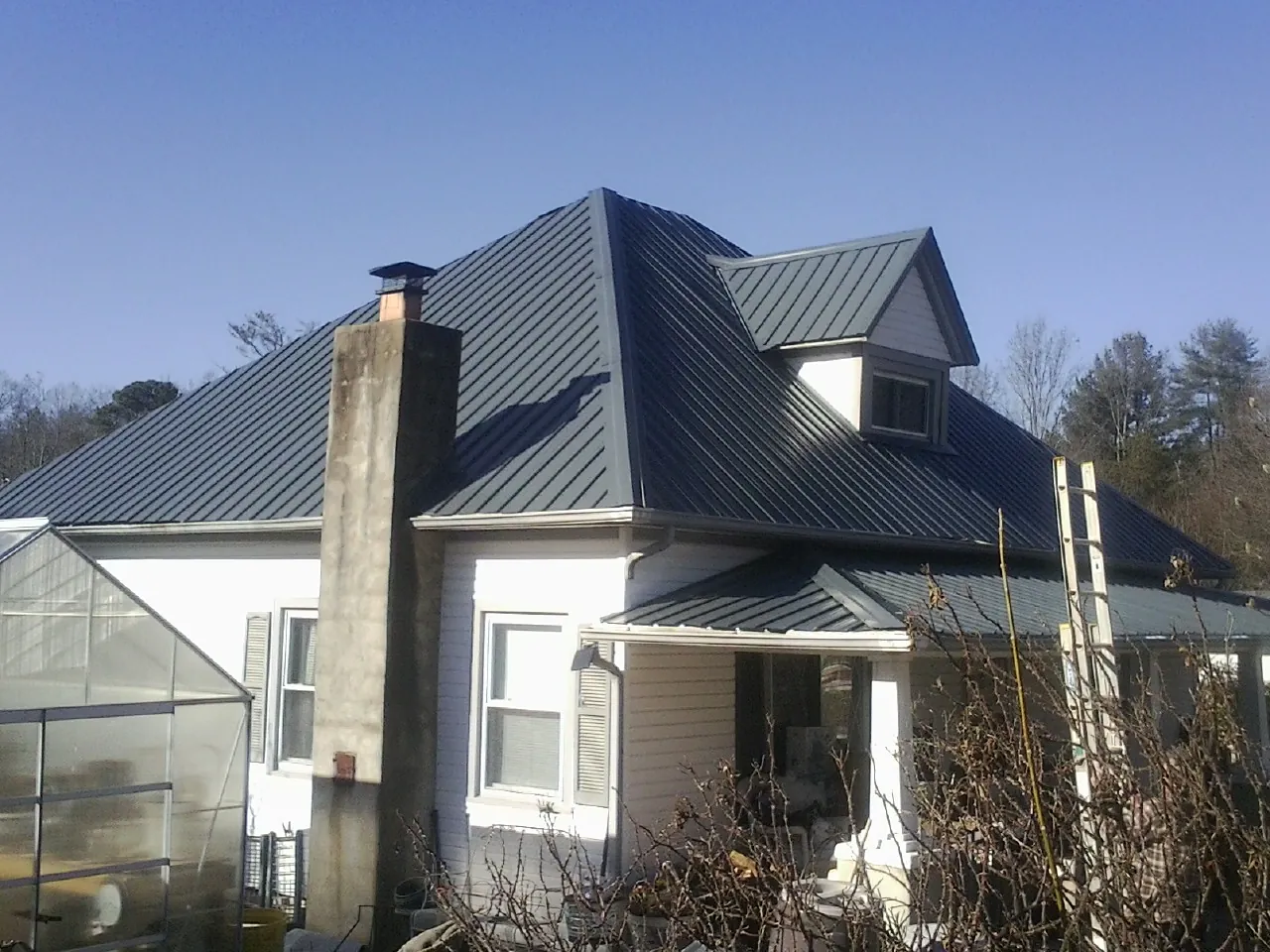 Dark blue standing seam metal roof on a white farmhouse with dormer — Slate & Tile Roof Repair by Roofing Brothers in Oak Harbor