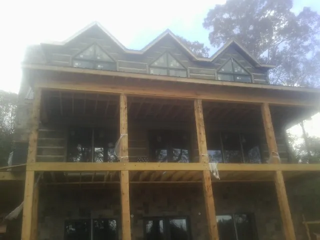 Dormers and porch framing on a large log home under construction — Roof Coating work by our crew in Oak Harbor
