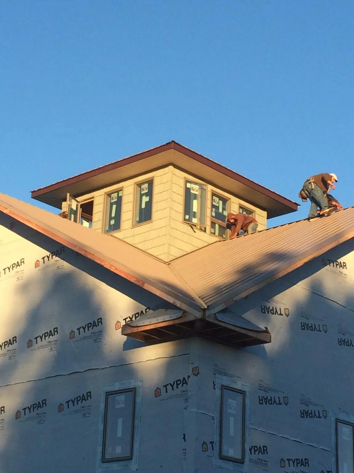 Roofers working around a rooftop cupola on a new metal roof at sunset — Roof Waterproofing in Oak Harbor by Roofing Brothers